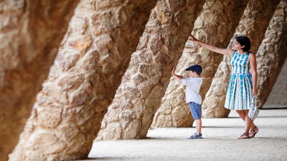 Little boy and woman walking through a tunnel of slanted support posts