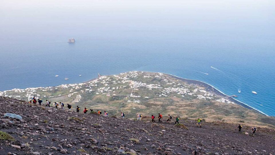 Hikers walking on Stromboli volcano, Aeolian Islands, Sicily, Italy. Ash and volcanic rock are the landscape of this climb.