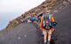 Group of tourists hiking on the Stromboli volcano in the Aeolian Islands, Sicily, Italy. Trekking backpack with the Terres d'Aventure logo.