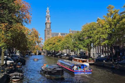 Tower of the Westerkerk church, autumn trees and people boating