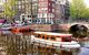 Small covered wooden boat moving up a canal within the famous canal ring