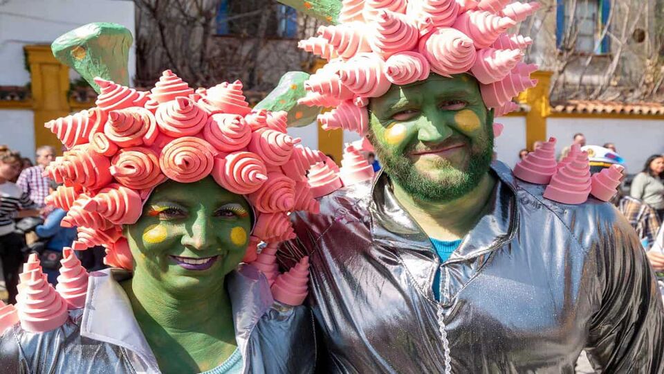 A couple with green face paint and pink swirls for hair stand together