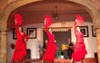 Three flamenco dancers wearing red perform on stage