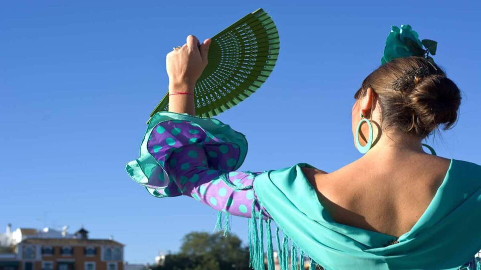 A flamenco dancer holds a fan up to the sky
