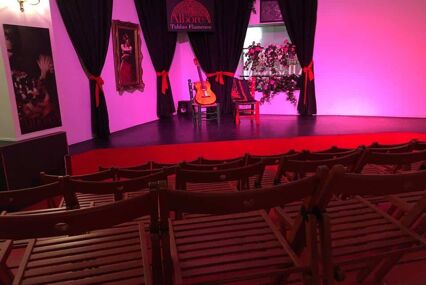 A stage set for a flamenco performance, with a guitar on a chair