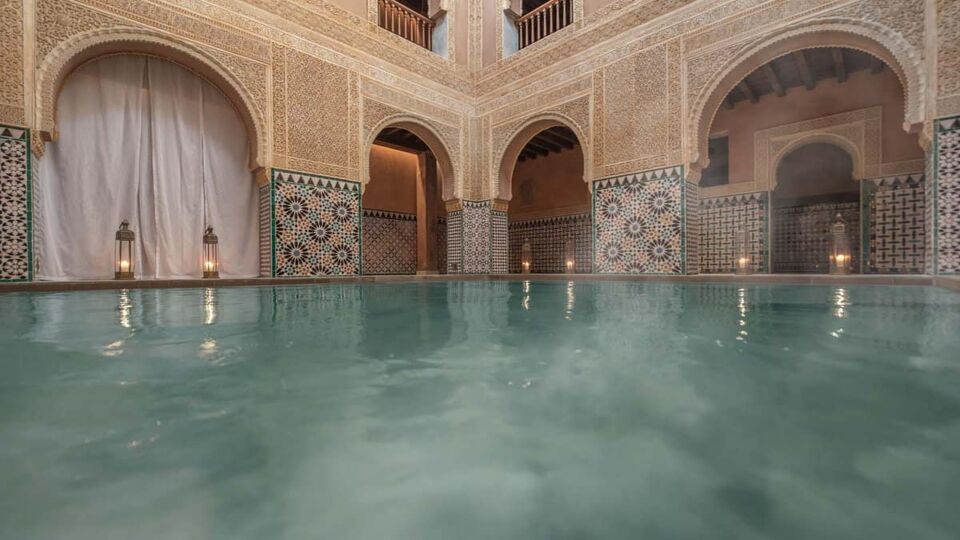 Interior of arabic bath with steaming pool and intricate Mudejar detail