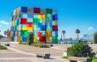 Brightly coloured glass cube building on a street