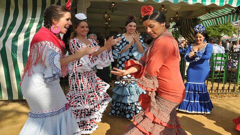 Four ladies in traditional dress dance on the street at the Feria de Abril