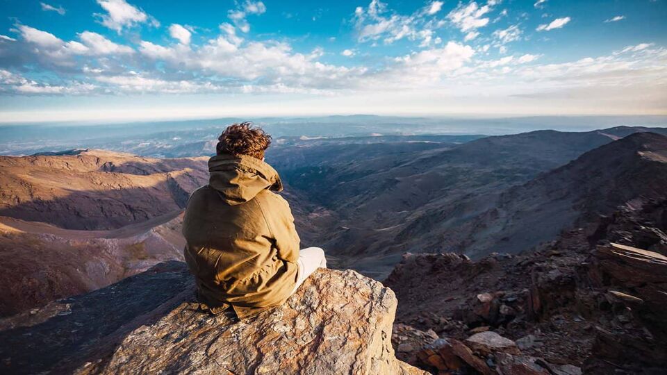 A hiker enjoying a beautiful landscape view from the summit of Mulhacen
