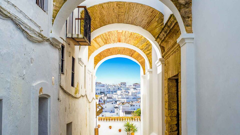 Looking trhough a beautiful arch with golden ceiling, out to rooftops of all white buildings