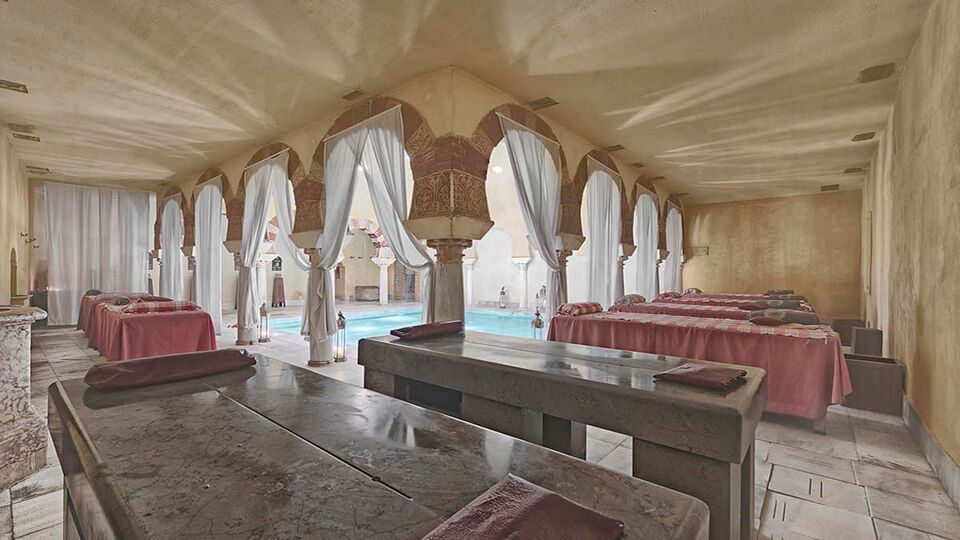 Stone hammam beds under arches beside the bathing pool