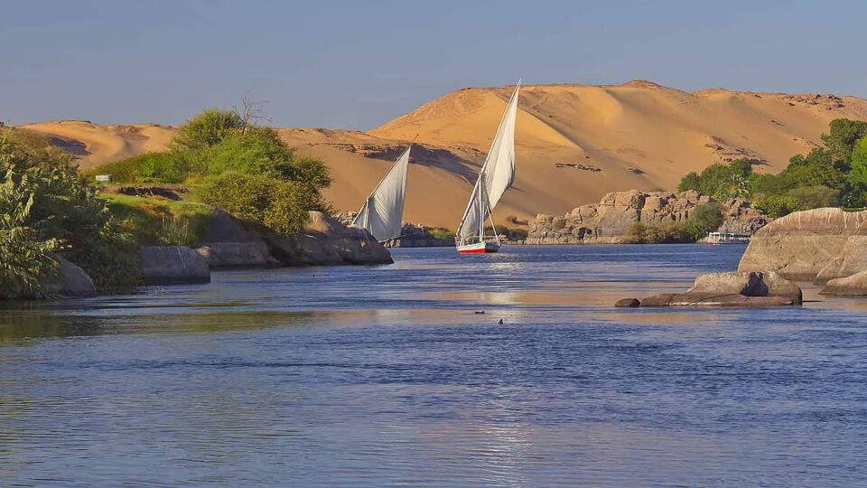 Typical sailing on the Nile. In the background sand hills and blue sky. Near Elephant Island. (Aswan, Egypt).