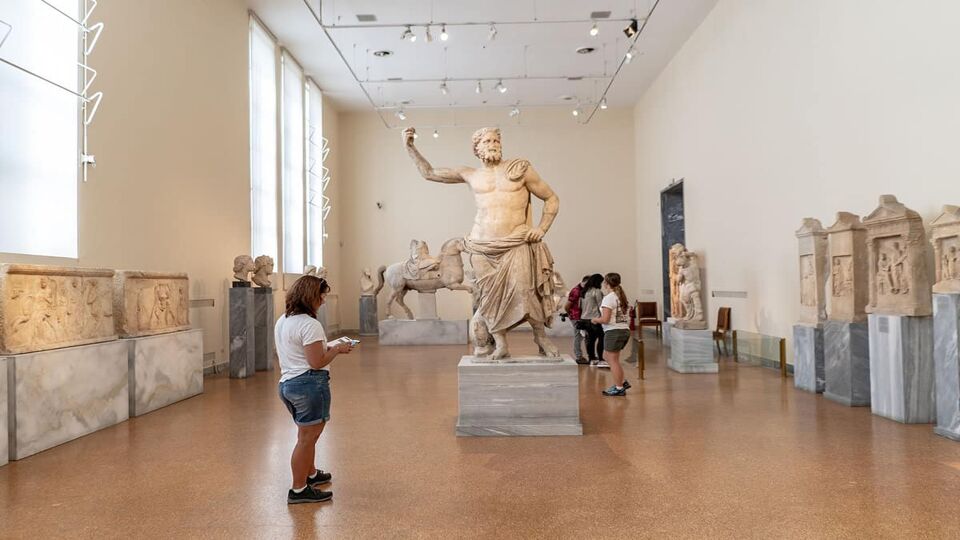A visitor looks at a sculpture of Poseidon in the museum