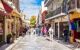 Pedestrians walking around a souvenir market street in Plaka