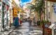 Tourists walk the streets lined with souvenir and gift shops and outdoor sidewalk cafes in Plaka