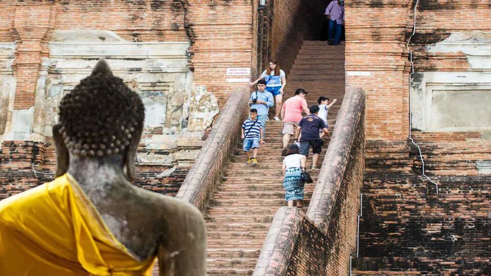 Steps in temple ruins with tourists, Buddha in the foreground