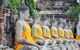 Row of statues of the Buddha in saffron robes