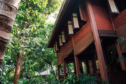 Teak house surrounded by lush greenery