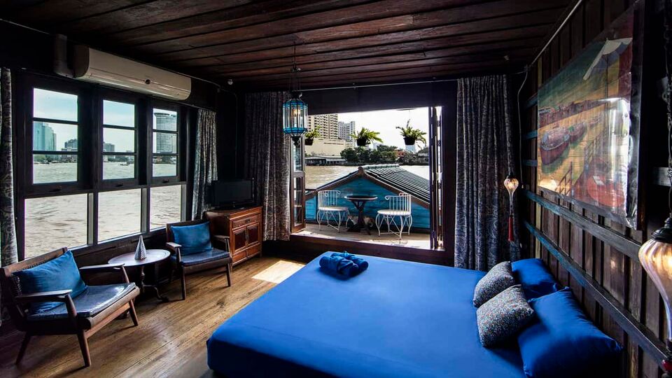 Wood panelled bedroom with blue accents and a balcony over the river