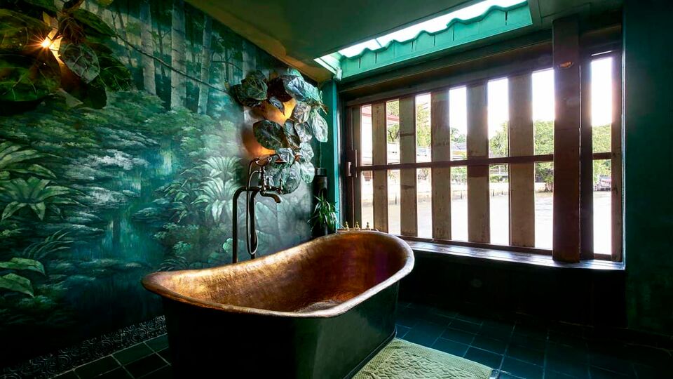 Bathroom with copper tub and wall painted with leaves