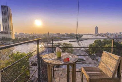 Small table on River Vibe sky bar overlooking river in Bangkok at sunset