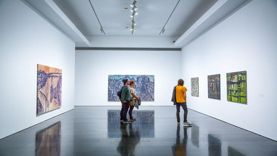 People looking at paintings on wall in the gallery