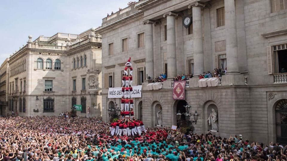 Human tower, surrounded by crowds, in front of the town hall