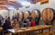 inside the cider house, people sitting at tables by big barrels