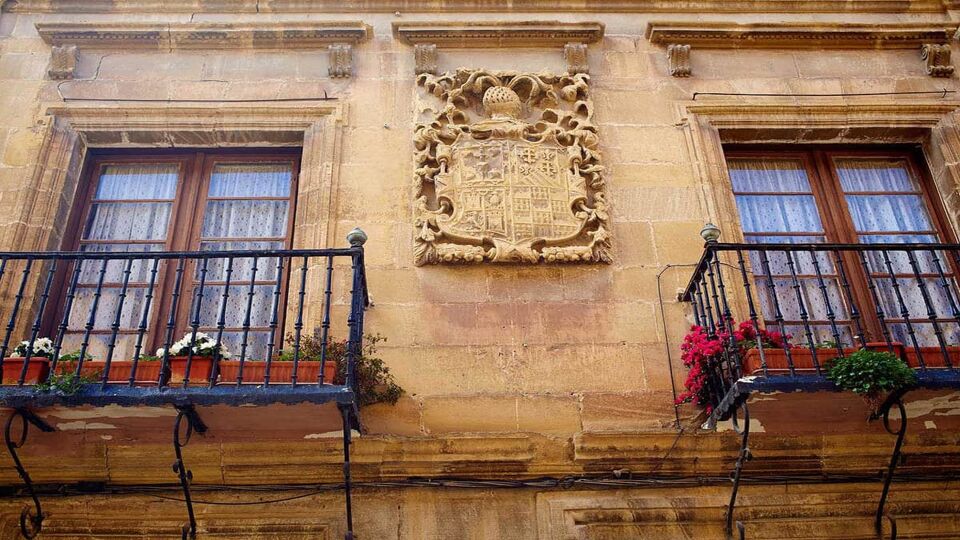 Close up of a building with two windows and stone coat of arms in between