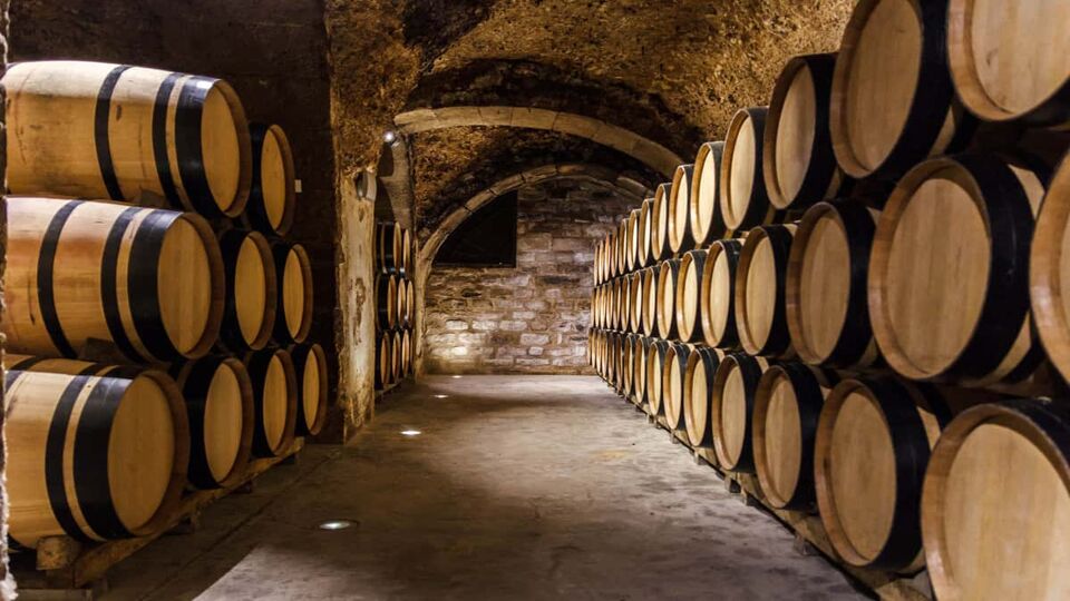 Stacked wooden barrels on either side of a passageway Inside a cellar in a cave