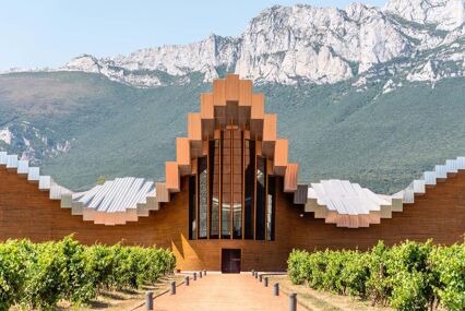 External view looking to the entrance. The curvy building has mountains behind