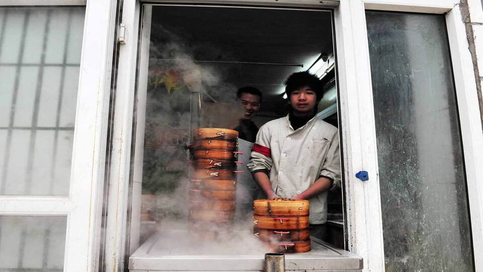 Man selling dumplings from white shop