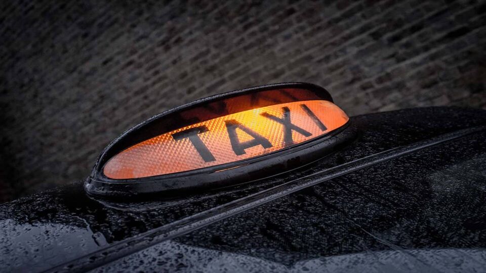 London black taxi cab waits in a backstreet with it orange light on to be hailed.