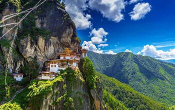 Buddhist temple built into a ledge on a cliff, surrounded by forested valleys