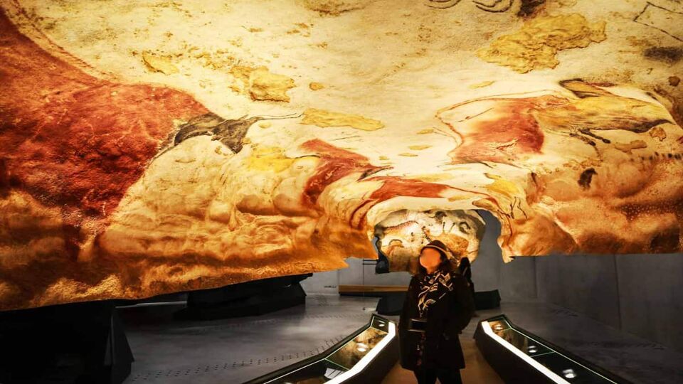 A visitor looks at the curved ceiling with cave paintings