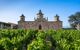 Wine fields and a grand building on a sunny day.