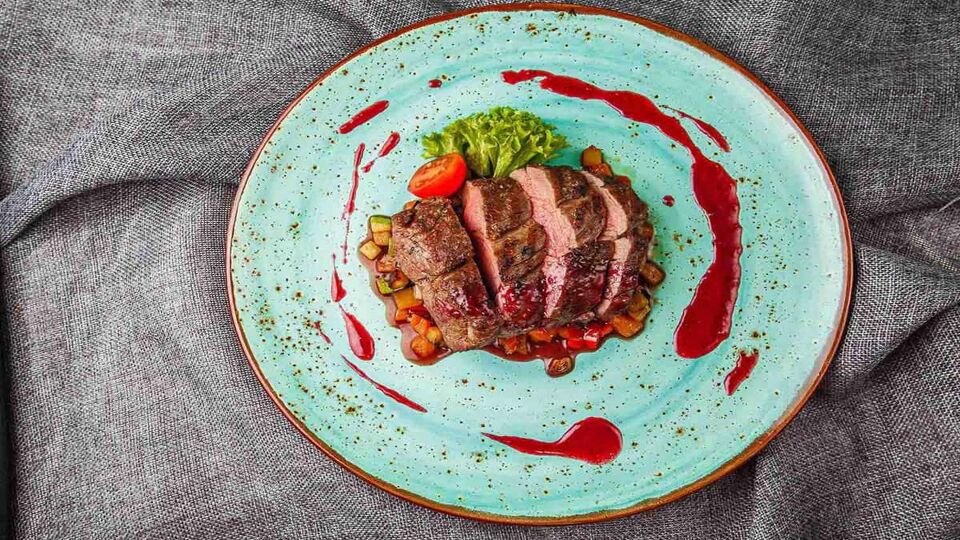 green plate with slices of rare duck breast on