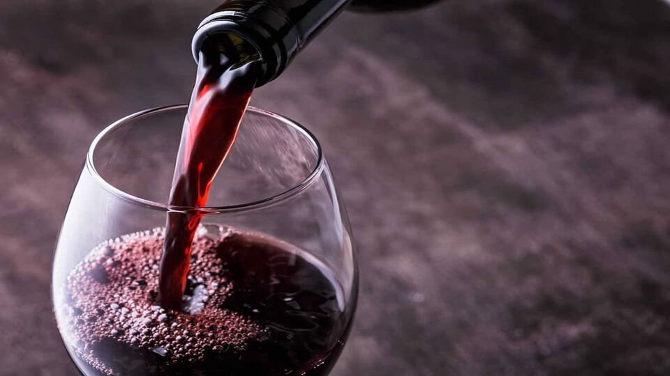 close up of red wine being poured into a glass
