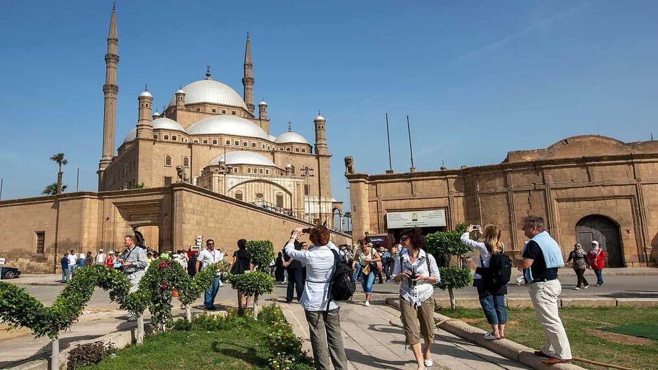 Tourists take photos of the magnificent Cairo Citadel (Citadel of Salah Al-Din) in Cairo, Egypt. It is a medieval Islamic fortification on Mokattam Hill.