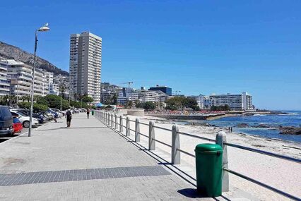 Mountains, hotels and deep blue water with waves at beach promenade
