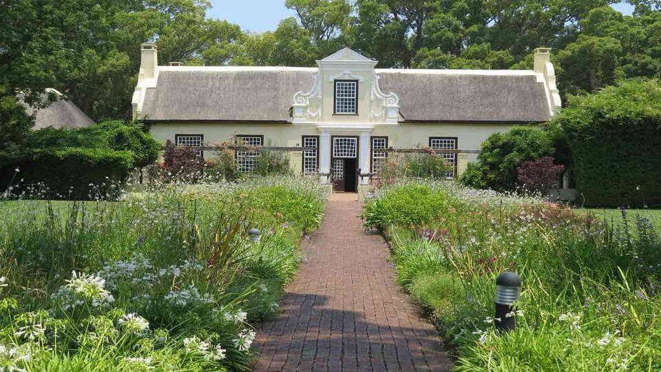 View of a house with a beautifully decorated front garden on a sunny day