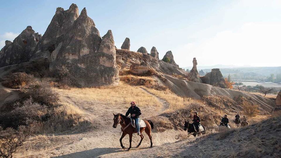 horse riders crossing a cappadocian landscape