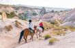 horse riders crossing a cappadocian landscape in the rose valley