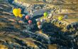 Many hot air balloons over a valley.