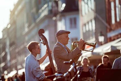Street musicians play music in the center of Copenhagen at sunset, the backlight. Copenhagen, Denmark