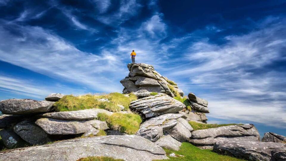 Killmar Tor: One of the highest peaks in Cornwall in Bodmin Moor. A single man stands on the top viewing in the far.