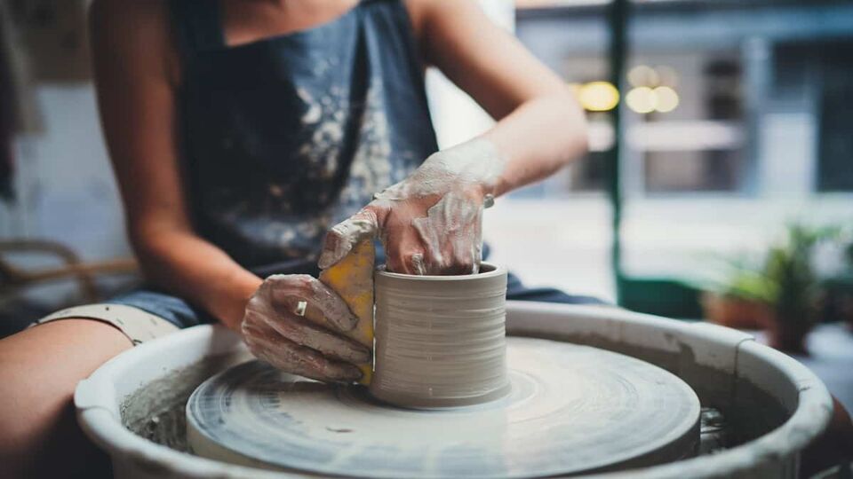 Woman making pottery on a pottery wheel in a Leach Pottery class