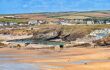 The beach and tidal swimming pool, with the town and hills beyond, during the summer heatwave. The hills are showing the effects of the summer drought.
