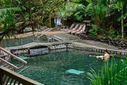 single woman bathing in outdoor pool surrounded by rainforest