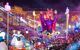 Brightly-illuminated carnival float surrounded by crowds